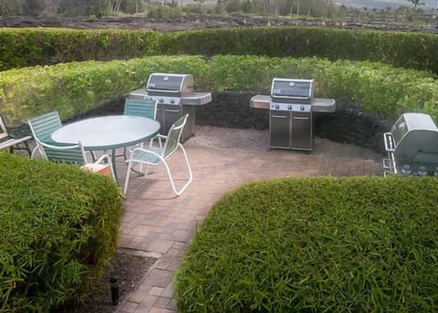 Private BBQ enclave surrounded by lush hedges, featuring multiple grills and outdoor dining space.