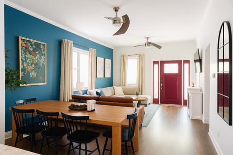 Open-concept living and dining space featuring bold blue accents, stylish modern décor.  Enjoy meals at the large dining table or unwind in the comfortable seating area—perfect for sharing great food, conversation, and relaxation in style.