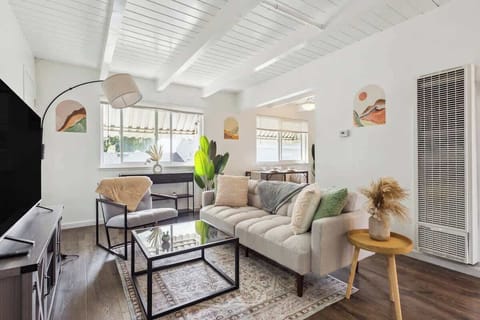 Bright and comfortable living room with lots of natural light, a cozy sofa, and a modern, welcoming setup.