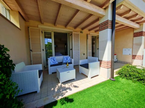 Elegant covered porch with relaxation area furnished with sofas and coffee table, perfect for enjoying an aperitif or reading a book in the shade. Direct access to the garden and French windows make the space bright and welcoming, ideal for enjoying the outdoors at any time of day.
