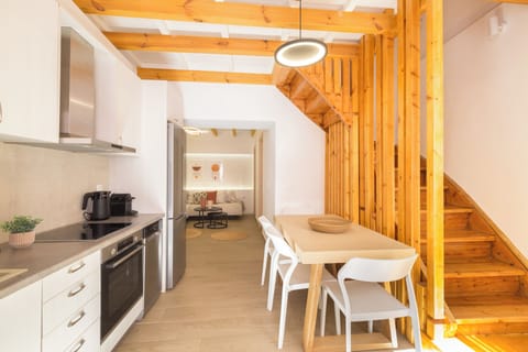 Bright kitchen with a dining table, connected to a staircase leading up