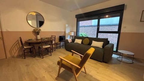 Espace salon avec canapé convertible, télévision et coin repas pour quatre personnes, ouvert sur la cuisine.