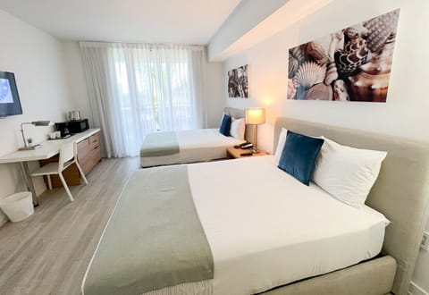 Spacious bedroom with a king-size bed, flat-screen TV, and bright natural lighting.