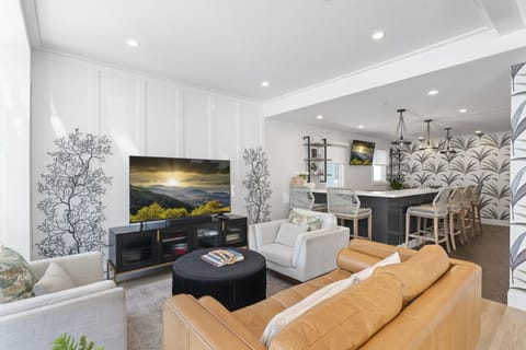 Bright living room w/ cozy seating, wall-mounted TV & open flow into dining & kitchen areas
