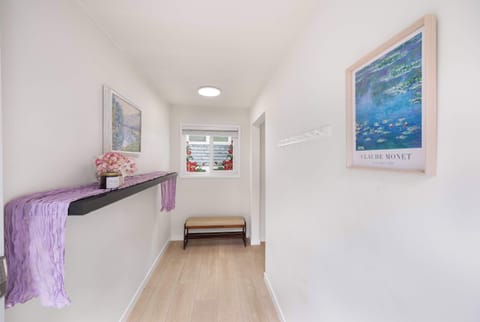 Simple designed hallway lined with few paintings,and windows framed with flower stickers.
