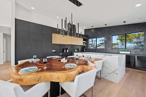 Natural beauty meets sleek design with a live-edge table, contemporary seating, and minimalist lighting. Fluted wood-finished cabinetry and wood-design floors complete this effortlessly chic space. 