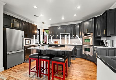 Sleek black cabinetry, gold hardware, and pops of red bring high contrast and bold personality to this stylish chef-ready kitchen.