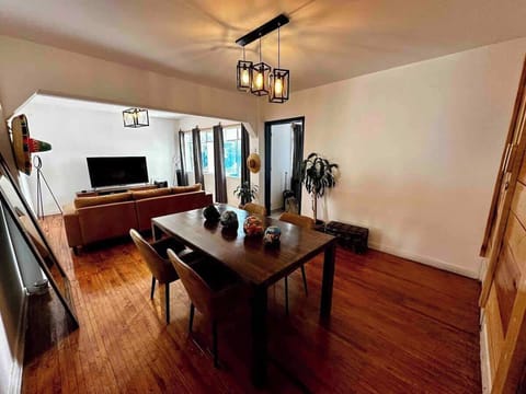 Sala tomada desde la esquina (cantina, mesa con 4 sillas, decoración, plantas, espejos, sombreros para decoración, sofá, televisión, alexa)