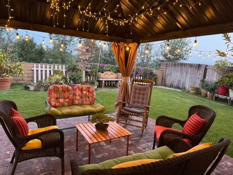 Relax under patio lights—rocking chair, cushions, and colorful backyard vibe.