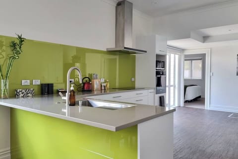 The large modern kitchen has a lime green splashback, an island bench with twin sinks, a built-in oven, and a microwave.