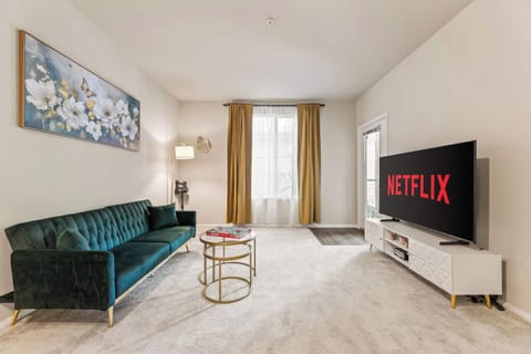 The living room with modern décor, gold detailing, and floor-length curtains framing the natural light beautifully.