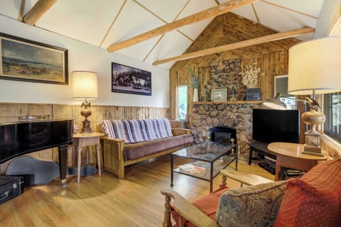 Eclectic and inviting, this mountain living room features exposed beams, a vintage piano, and a small stove framed by a stone surround—blending rustic charm with artistic touches for the perfect place to unwind.