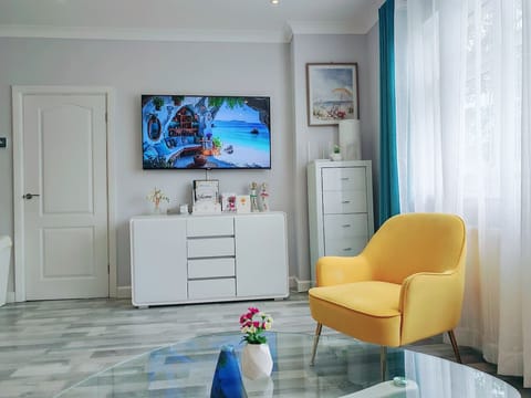 An open-plan layout combininBright lounge with TV and colourful seating.g the kitchen, dining area, and living space for a bright and social atmosphere.`