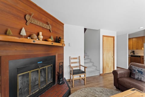 Living area with ample seating, wood burning fireplace, TV, and balcony access.