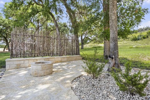 Gather around the stone fire pit in this inviting outdoor area, surrounded by natural beauty and a rustic privacy fence, perfect for evening conversations under the stars.