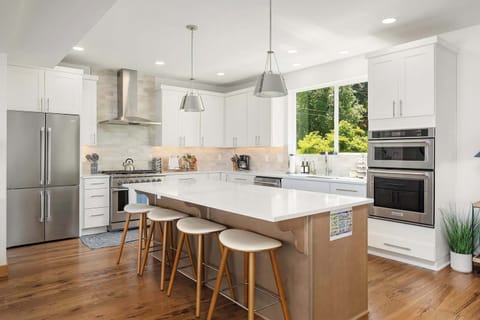 Meal prep meets sunlight, double ovens, stainless appliances, white cabinets and a window above the sink for home-cooked meals.
