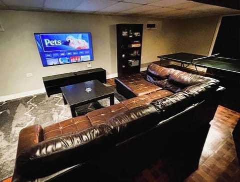 Basement lounge with comfy sofa, TV, and ping pong.