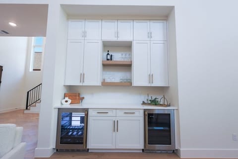 Cheers to convenience! This built-in dry bar features dual wine fridges, open shelving for glassware, and plenty of storage—perfect for entertaining or winding down in style.