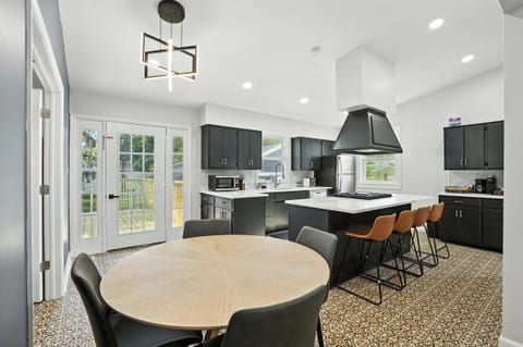 Sunlit kitchen with French doors to the deck, island seating, and a cozy breakfast nook—perfect for morning coffee or late-night snacks!