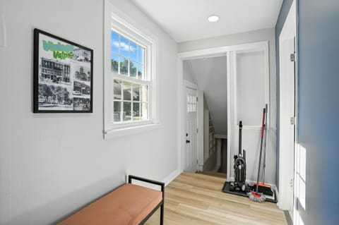 This bright mudroom—just off the kitchen and adjacent to the second bathroom—offers a practical drop zone with a cozy bench, cleaning essentials, and access to the back stairwell and side entry.