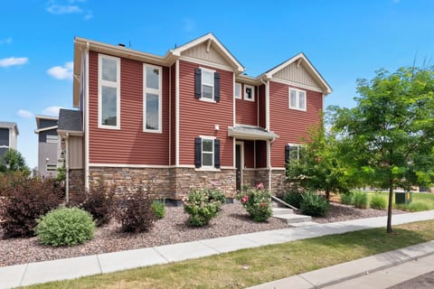 Two-story home with red siding, stone accents, and welcoming entrance.
