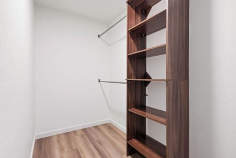 Spacious walk-in closet with wooden shelves, hanging rods, and modern design.