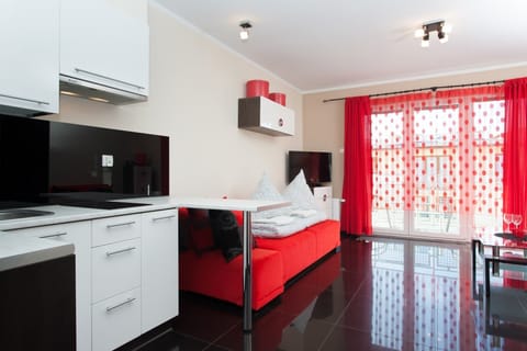 A small dining setup next to the kitchenette, featuring sleek white cabinets and black countertops for a clean, minimalist look.