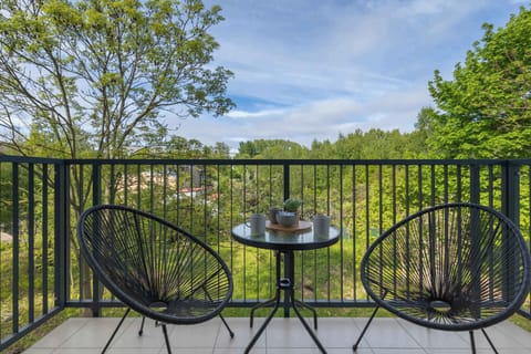A charming balcony overlooking green trees, furnished with a functional table and two comfortable chairs, is the perfect place for morning coffee or evening relaxation.