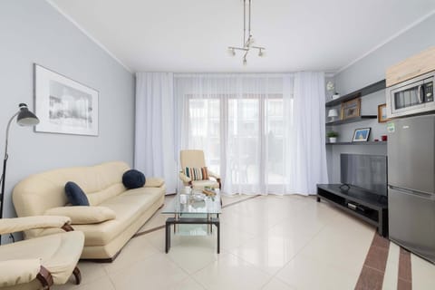 A bright and inviting living room with a comfortable sofa, a TV, and access to a sunny terrace. The perfect spot for relaxation and quality time.