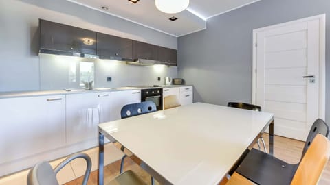 Fully equipped kitchenette with electric cooktop, electric kettle, refrigerator, freezer, oven, toaster, dishwasher and table with chairs.