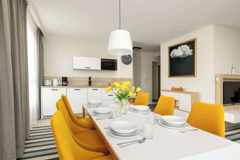 A modern dining room with a large table, elegant chairs and stylish lighting. The space is bright and airy, ideal for shared meals and gatherings.