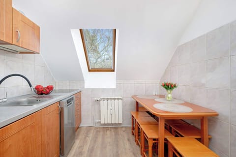 A traditional-style kitchen with wooden cabinets, white countertops, and modern appliances, including a kettle and coffee maker.