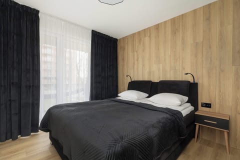Dark curtains and the wooden wall behind the bed create the perfect atmosphere for relaxation and restful sleep.