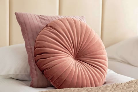 Close-up of the pink round pillow on the bed, adding color and coziness to the bedroom.