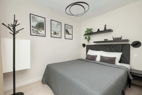 A modern bedroom with a double bed, wall-mounted reading lamps, and minimalist décor. The space is bright and inviting, ideal for restful sleep.