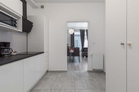 A sleek and modern kitchen with white cabinetry, a black countertop, and ample space for meal preparation.
