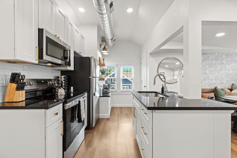 Fully equipped modern kitchen with stainless steel appliances and sleek black countertops.