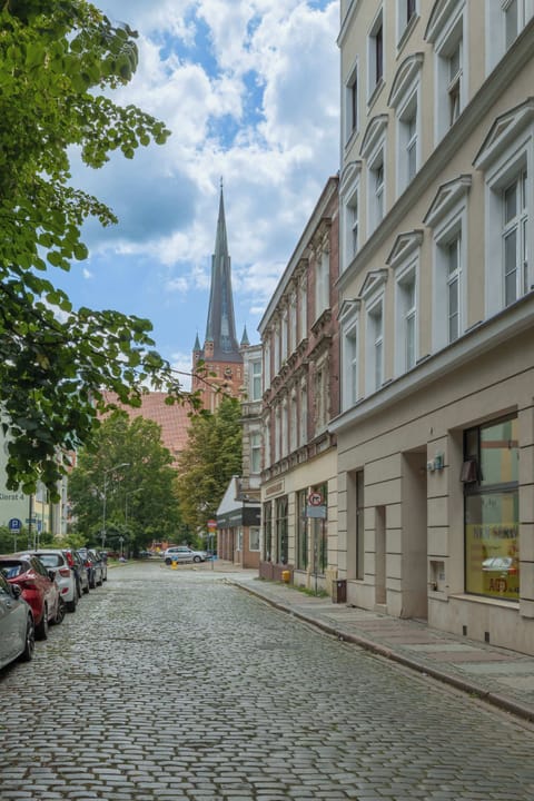 A close-up of the building’s main entrance, highlighting the polished stonework and well-maintained surroundings. The entrance feels modern and inviting.