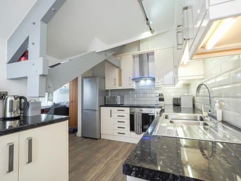 Underneath of the staircase, sink, worktop, kettle, fridge, freezer and wall cabinets