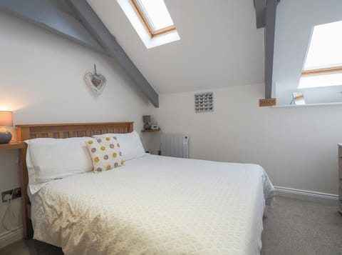 Double bed, lamp on a shelf by the bed, Velux window