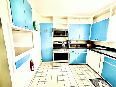 This playful kitchen bursts with personality, featuring vintage blue cabinets, stainless steel appliances, and bright tile floors.