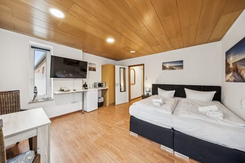 Gemütliches Studio mit Doppelbett, TV, Pantry mit Kühlschrank und Mikrowelle, warmem Holzdekor und viel Platz – ideal für einen entspannten Aufenthalt.