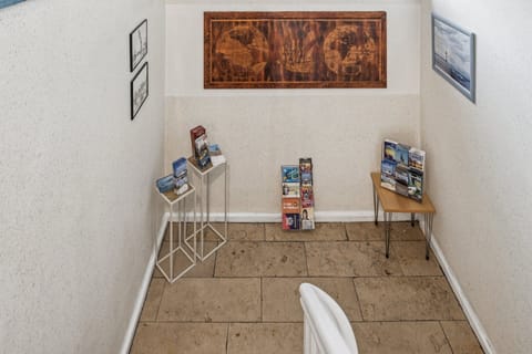 Infoecke im Treppenhaus mit Prospekten, Karten und regionalen Tipps auf kleinen Tischen – praktische Orientierung für den Aufenthalt.