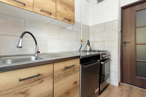 A similar view of the kitchen, highlighting the upper and lower cabinets, sink, and a tiled backsplash.