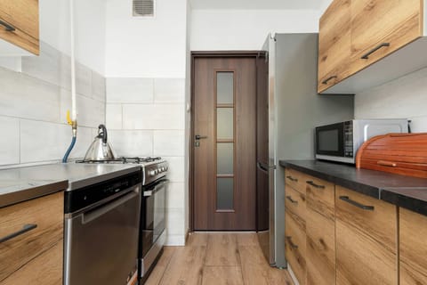 A modern kitchen with wooden cabinetry, black countertops, and a stainless steel sink.
