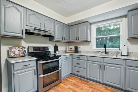 Create meals with ease in this bright kitchen featuring stainless steel appliances, granite countertops, and stylish gray cabinetry. A window view and warm wood floors make it both functional and inviting for your stay.