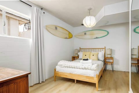 Cozy and stylish bedroom featuring a queen bed, soft lighting, and playful surf-inspired decor. Enjoy a restful stay with plush bedding, ample natural light, and thoughtful touches for comfort.
