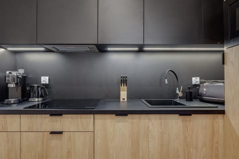 A modern kitchen with sleek black cabinets, wooden accents, and state-of-the-art appliances.
