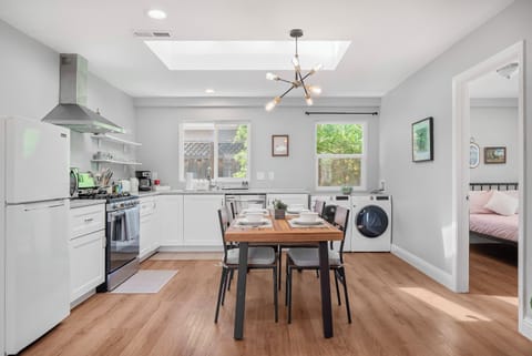 Bright kitchen with skylight, dining table, and washer-dryer combo next to the bedroom.