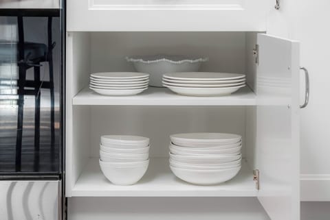 Full kitchen : Cabinet with neatly stacked plates, bowls, and glass storage containers.